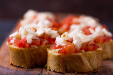 Bruschetta small sandwiches antipasto set with tomato, mozzarella, garlic and basil on black background