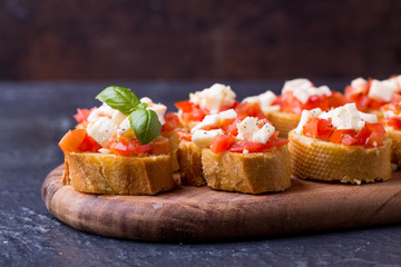 Bruschetta small sandwiches antipasto set with tomato, mozzarella, garlic and basil on black background