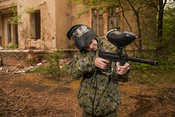 young boy playing paintball. boy aiming a paintball gun. Boy in camouflage clothing. boy in a protective suit. Boy in a protective mask. game of war. war game. Boy shoots a gun.