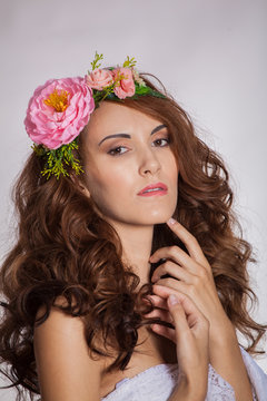 young and beautiful brown-haired woman on a white background with flowers in her hair