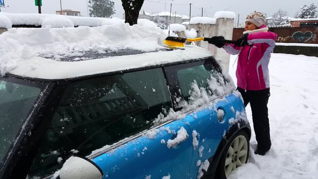 Woman clears mini cooper from the snow