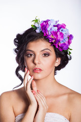 young and beautiful brunette on a white background with flowers in her hair