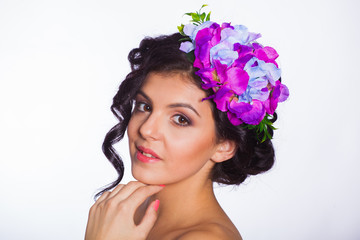 young and beautiful brunette on a white background with flowers in her hair