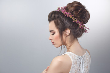 Beauty portrait of sexy bride with a wreath of heather in hairstyle isolated on gray background.