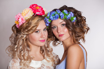 Two young and beautiful girls on a white background with flowers in her hair