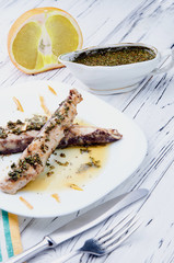 Fried fish with orange sauce and herbs. A plate of food in foreground, half orange and saucers with sauce in the background. European, Asian, African dish. Fresh farm products.