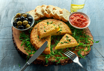 Spanish classic tortilla with potatoes, olives, tomatoes, roccula, bread and herbs.