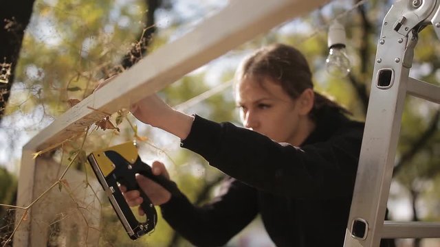 decorators draping wedding arch near sea with staple gun