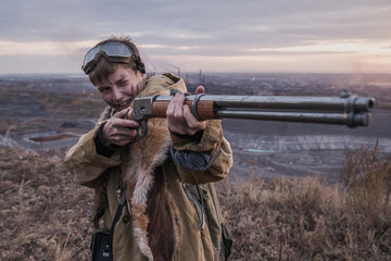 young boy standing on a mountain with a gun. post-apocalyptic world. boy with fox skin on his shoulders. boy aiming a gun. teenager forest hunter. Apocalypse