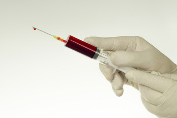 Hand in white glove with syringe