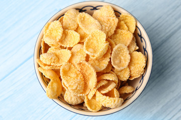 Bowl with cornflakes on white wooden background