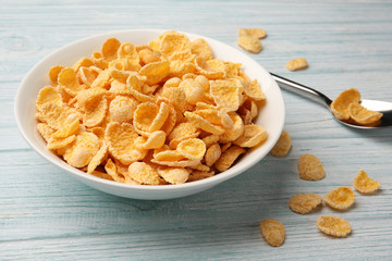 Bowl with cornflakes on white wooden background