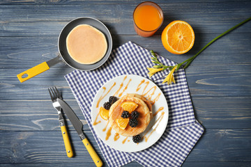 Stack of fresh pancakes with fruits on wooden table