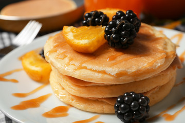 Stack of fresh pancakes with fruits on plate, closeup