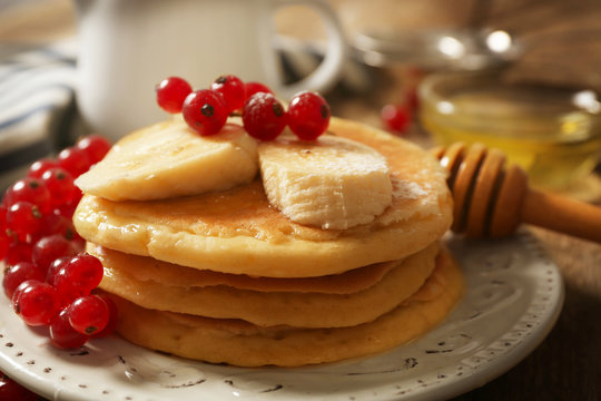 Stack of fresh pancakes with berries on wooden table