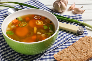Soup with fresh vegetables and bread on napkin