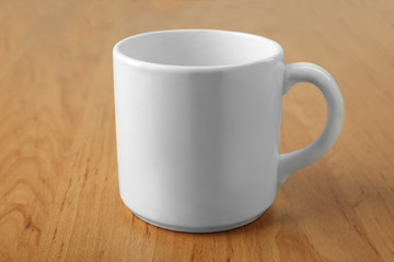 Blank ceramic cup on wooden background