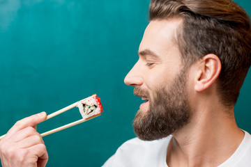Man eating sushi with chopsticks on the green background