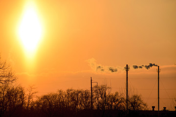 Naklejka premium Smoke from the boiler pipes at sunset. Winter landscape