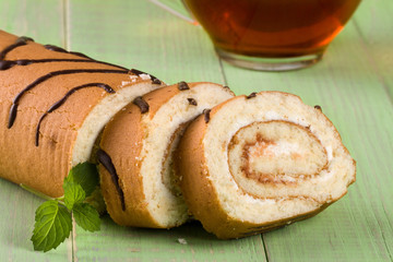 Biscuit swiss roll on a green wooden background