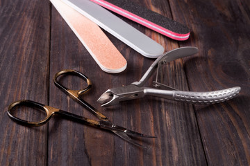 nail scissors file and clippers to remove the cuticle care products on a dark wooden background