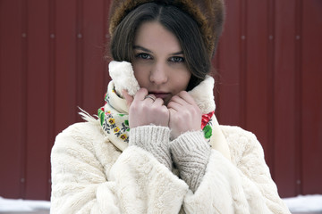 The young beautiful girl with dark hair in a bright sheepskin coat on a background of a winter landscape&nbsp;