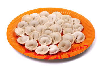 Frozen pelmeni laying on the orange plate