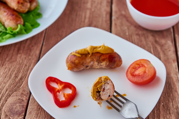 Grilled sausages with vegetables on a wooden background.