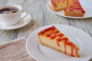 Slice of the New York cheesecake on a white plate on a wooden background .