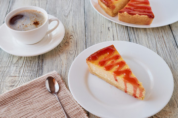 Slice of the New York cheesecake on a white plate on a wooden background .