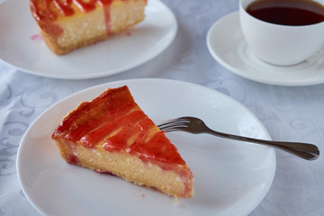 Slice of the New York cheesecake on a white plate on a wooden background .