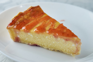 Slice of the New York cheesecake on a white plate on a wooden background .