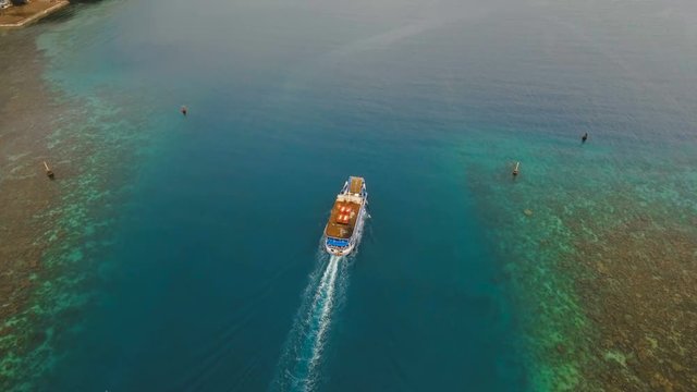Aerial view passenger ferry floats in the blue sea.Asian passenger boat floating in the ocean.Philippines, Camiguin. Passenger ferry boat Camiguin to Mindanao. 4K video.Travel concept. Aerial footage.