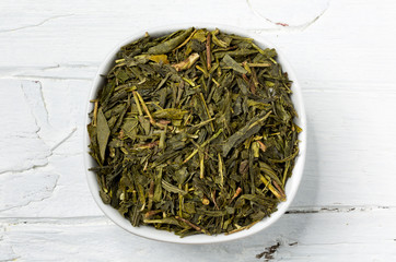 Fototapeta na wymiar Green tea leaves bancha in white bowl on wooden background.
