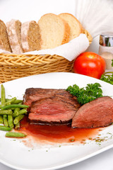 Steak in red wine with a side dish of asparagus on a white plate