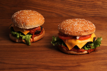 Homemade hamburger with double cheese, tomatoes, onions and grated carrots on a wooden table, unhealthy food. 