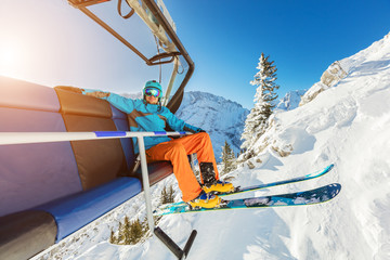 Skier sitting at ski chair lift in Alpine mountains - Powered by Adobe