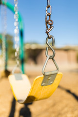 Close up of an child's yellow swing at public playground - vertical view