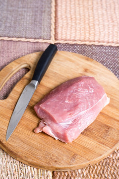 Raw pork meat on the cutting board with knife