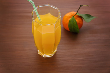 A glass of orange drink in a glass and the fruit of the Mandarin orange with leaves on the 

table. Citrus juice in glass on brown background. Plenty of space for text.