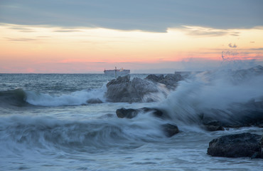 Wave in rough sea at sunset, long exposure