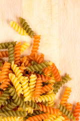 Raw colored macaroni on the wooden board with copy space