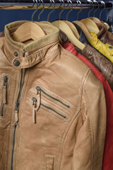 Many colored  leather jacket hanging on rack on blue background