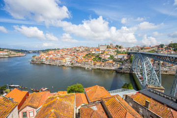Fototapeta na wymiar View of the historic city of Porto, Portugal with the Dom Luiz bridge. across the Douro river and the traditional rabelo boats