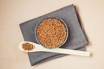 Buckwheat groats in bowl and wooden spoon