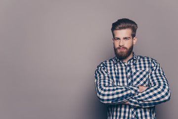 Confident bearded man with crossed hands on gray background