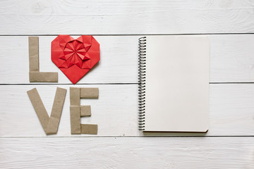 Red origami heart, craft paper folded letters Love inscription on white painted rustic rural barn wood background. Nice Valentines day holiday greeting card, postcard template.