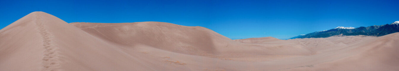 Fototapeta na wymiar A panoramic photo of the sand dunes and mountains at Great Sand Dunes National Park in Colorado.