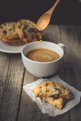 Motion of Drop falling to Hot Coffee with Cookies on Wood Backgr