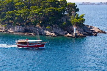 Fototapeta na wymiar Red boat and lighthouse in water near Dubrovnik